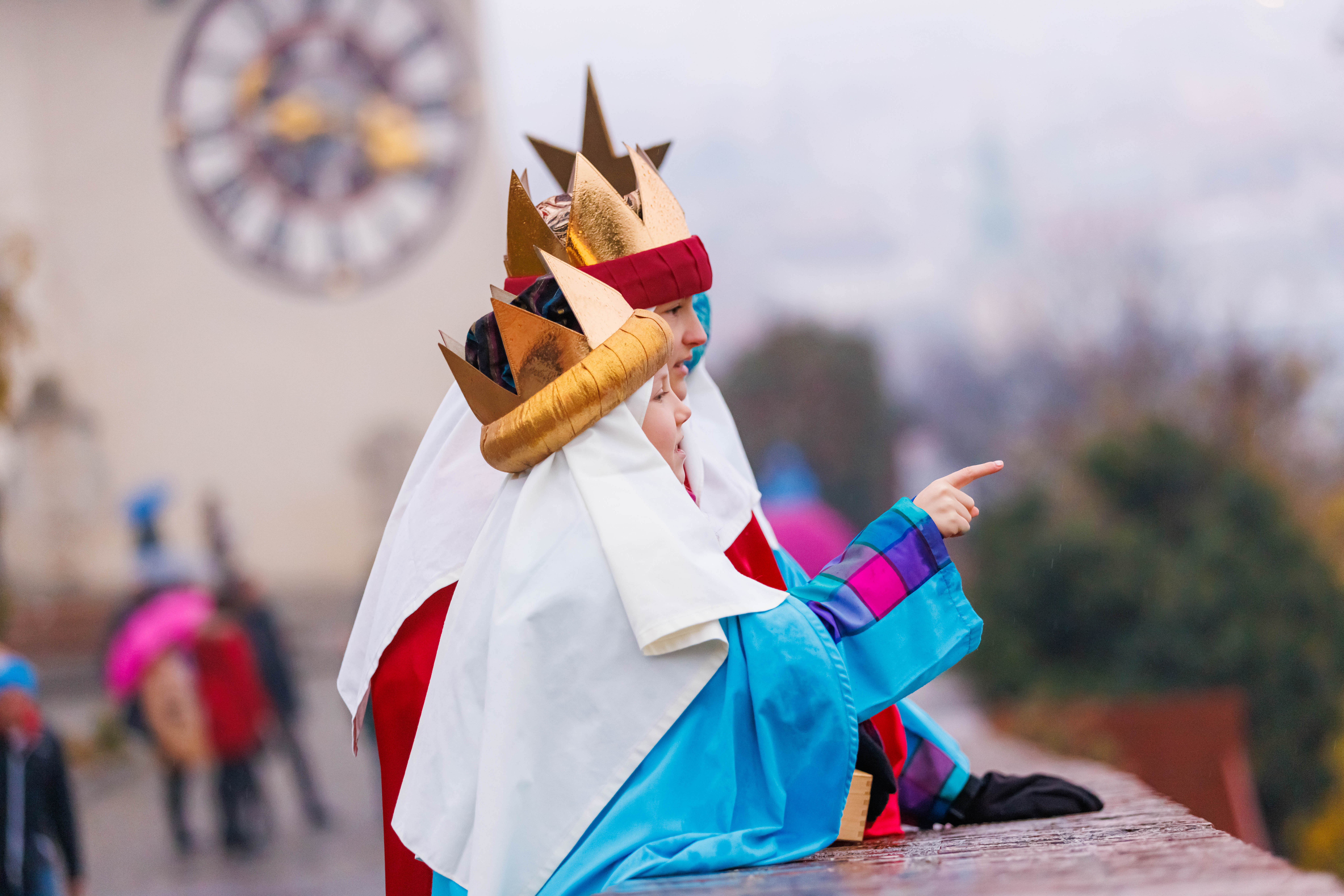 Zwei Kinder mit goldenen Kronen schauen von einer Aussichtsplattform aus auf die Stadt herab.